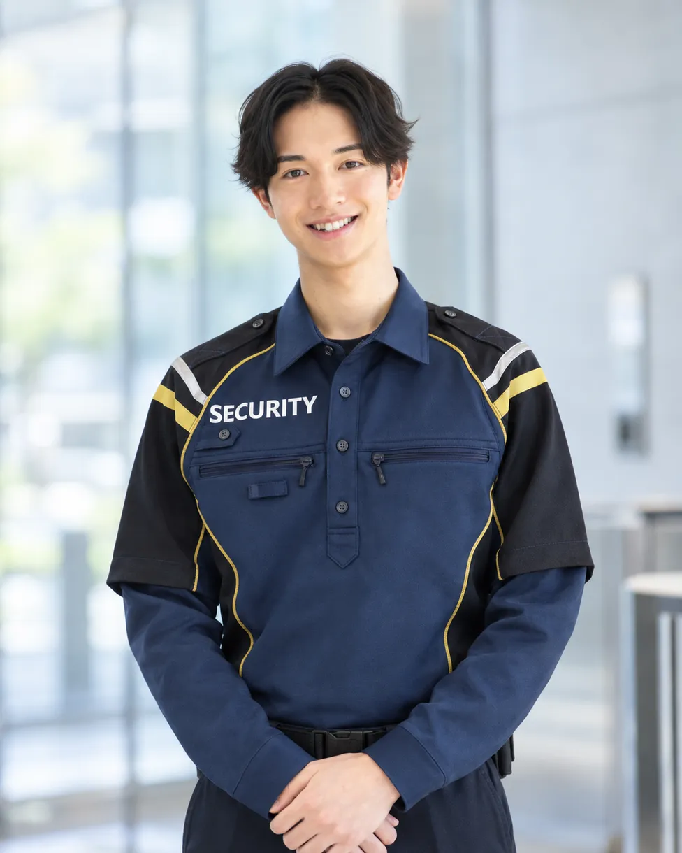 制服姿で笑顔で立つ若手男性スタッフ